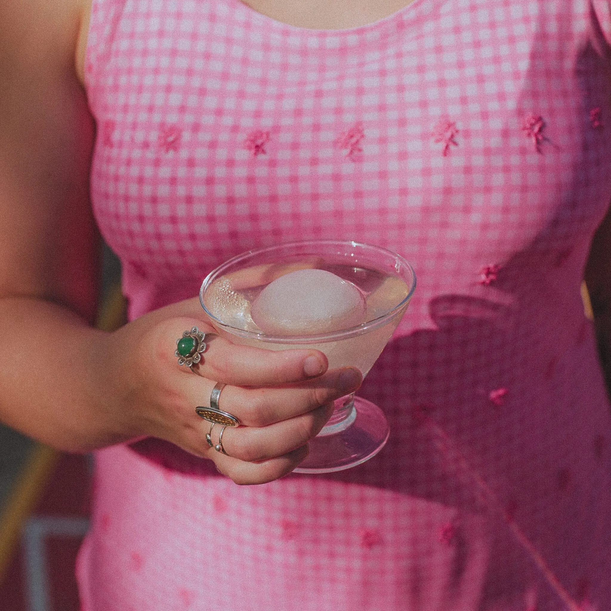 Woman wearing a pink vintage dress holding a clear cocktail